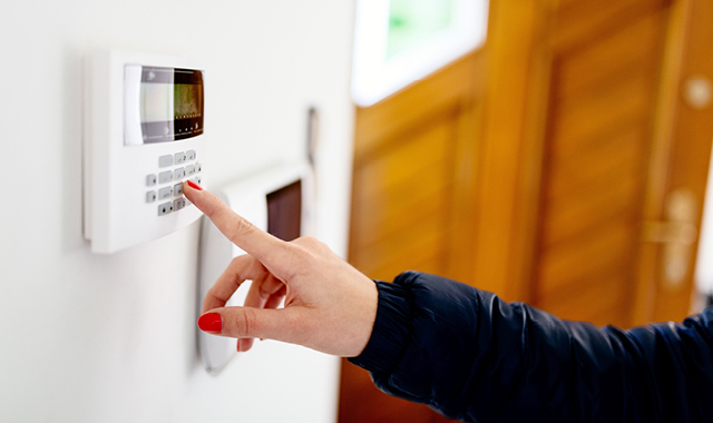 A woman enters a security code into her home smart alarm system.
